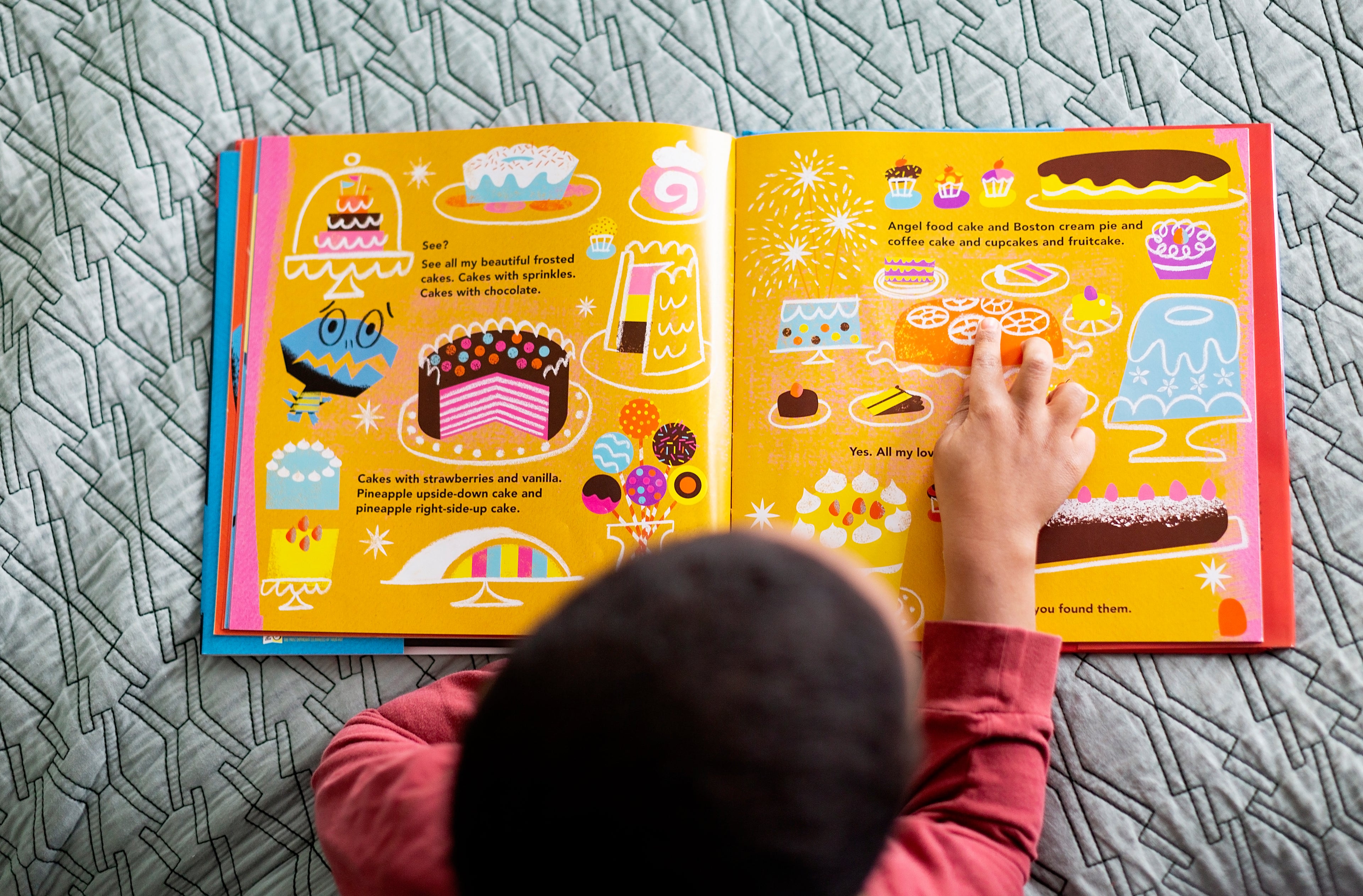 Child reading book with pictures of cakes.
